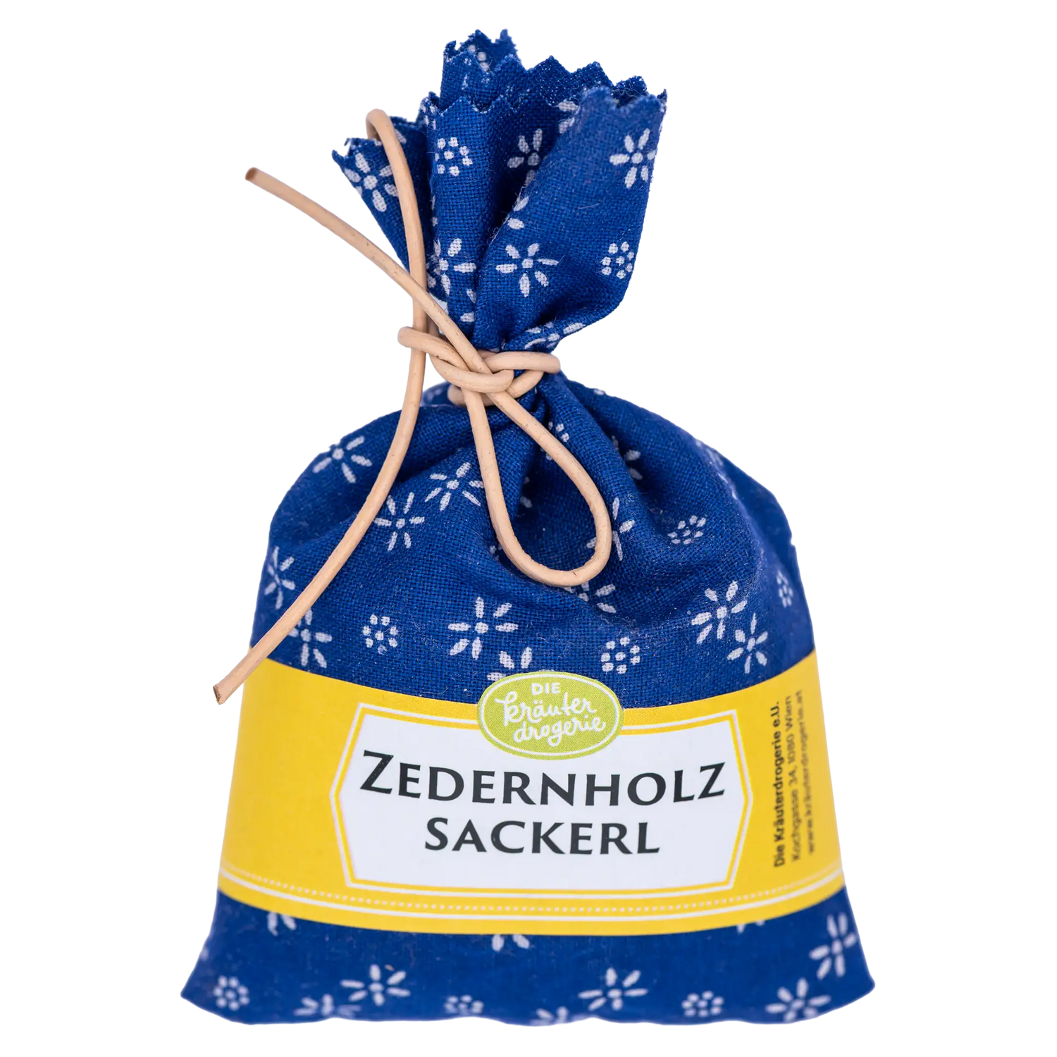 Handgenähtes Zedernholzsackerl der Kräuterdrogerie aus blauem Blaudruckstoff mit weißem Blütenmuster. Der kleine Duftbeutel ist mit einer hellen Kordel verschlossen und hat eine gelbe Banderole.